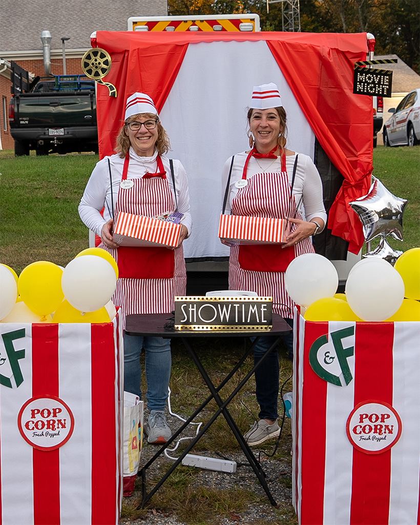 Two women dressed as popcorn vendors at a trunk or treat.